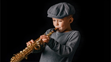 En pojke i keps spelar saxofon.