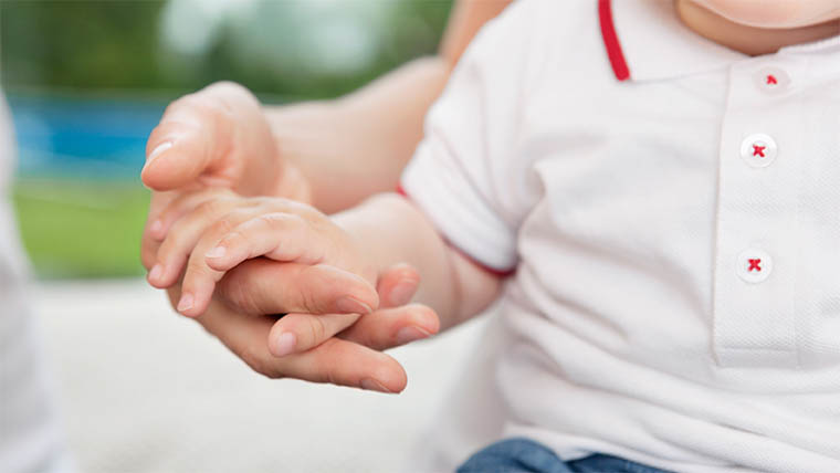 Ett barn håller en vuxen i handen