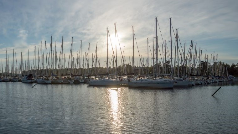 En hamn med segelbåtar, solnedgång och hav. 
