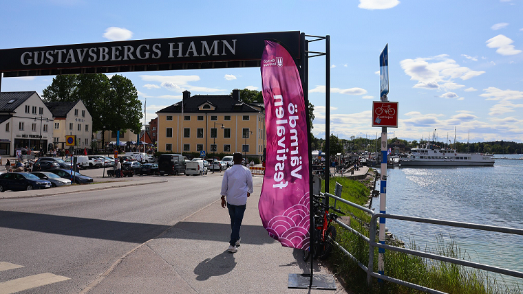 Person går förbi en flagga med texten
"Värmdöfestivalen" nere i Gustavsbergs hamn.