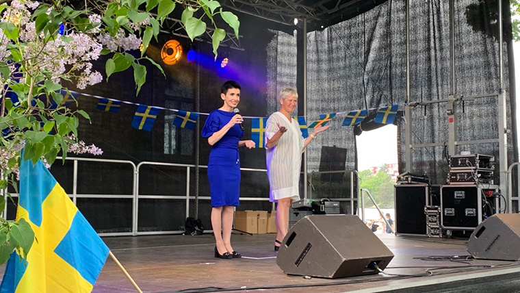 Deshira och Cecilia står på en scen med svenska flaggor i bakgrunden 