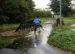 Bild på man som cyklar på översvämmad väg