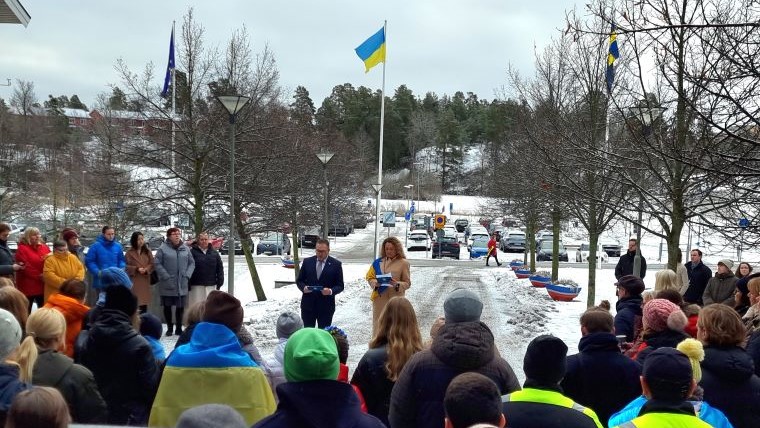 En människosamling och den ukrainska flaggan hissad. 