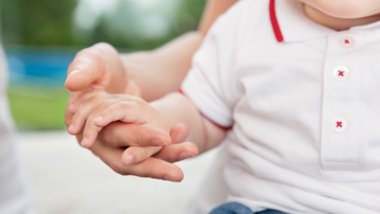 En vuxen håller ett barns hand. 