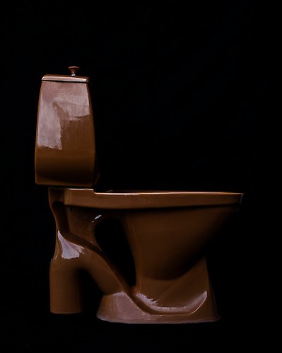 En WC i brunt porslin från sidan mot svart bakgrund.